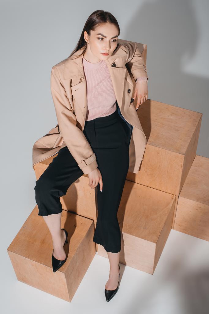 модна жінка сидить на дерев'яних блоках
 - Фото, зображення