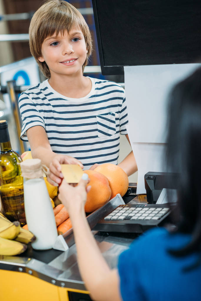 menino fazendo pagamento no supermercado
 - Foto, Imagem