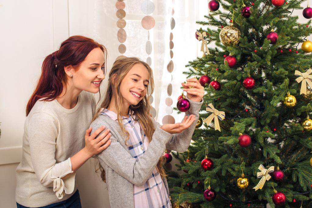 Moeder en dochter versieren kerstboom  - Foto, afbeelding