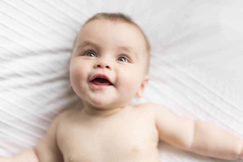 Χαριτωμένο χαρούμενο κοριτσάκι 7 μηνών σε πάνες που λέει ψέματα και παίζει - Φωτογραφία, εικόνα
