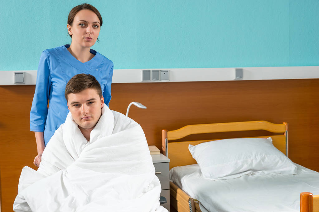 Vonzó fiatal nővér húzza kerekesszék beteg beteg fedéllel - Fotó, kép