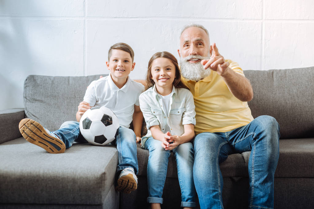 Abuelo y sus nietos viendo lo más destacado del partido de fútbol
 - Foto, Imagen