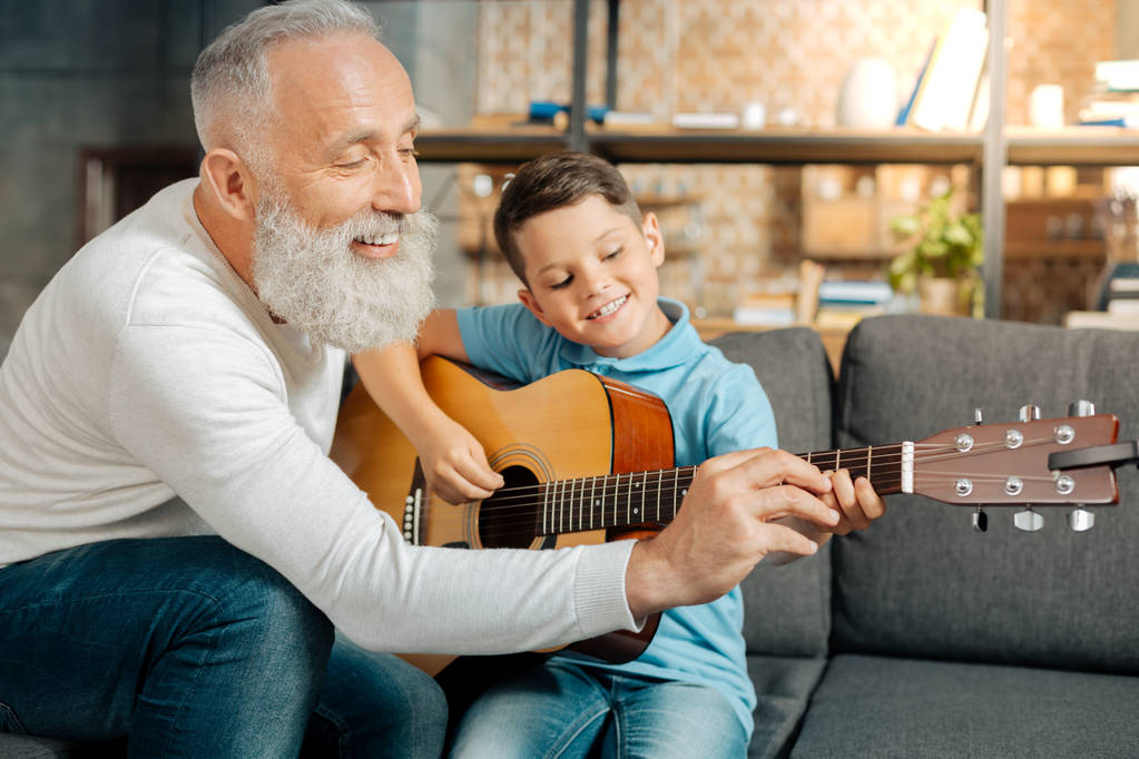 Amante abuelo enseñando nieto cómo sostener la guitarra
 - Foto, imagen