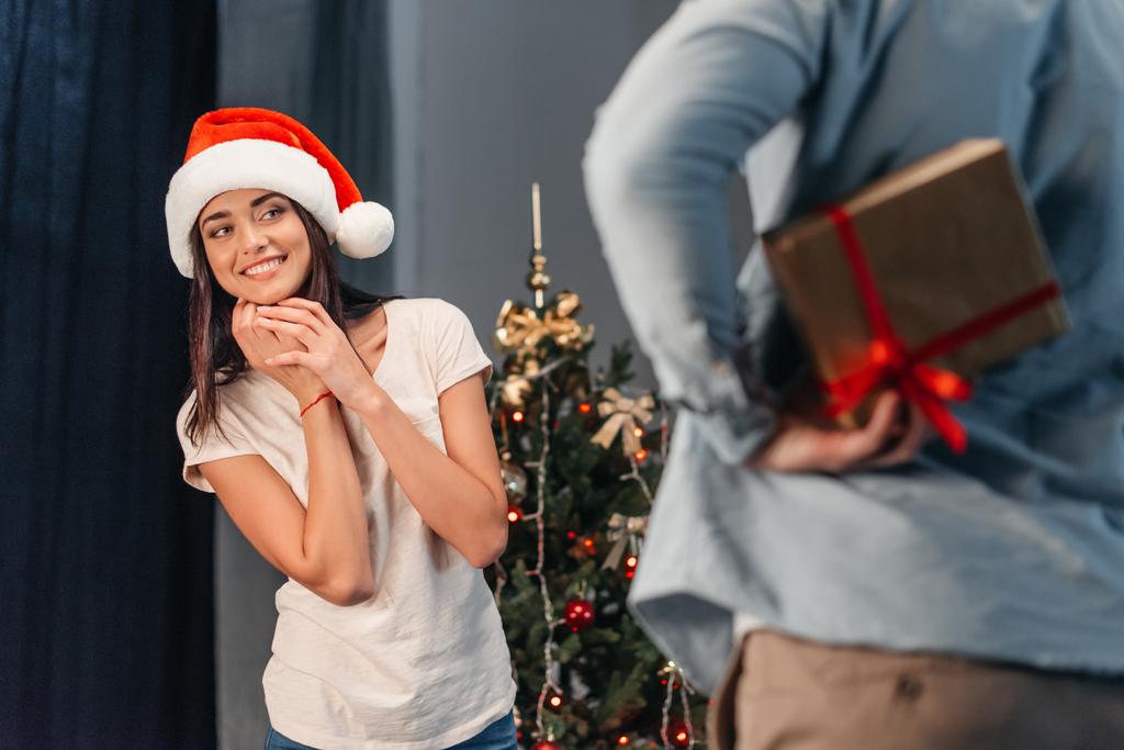 мужчина преподносит рождественский подарок своей девушке
  - Фото, изображение