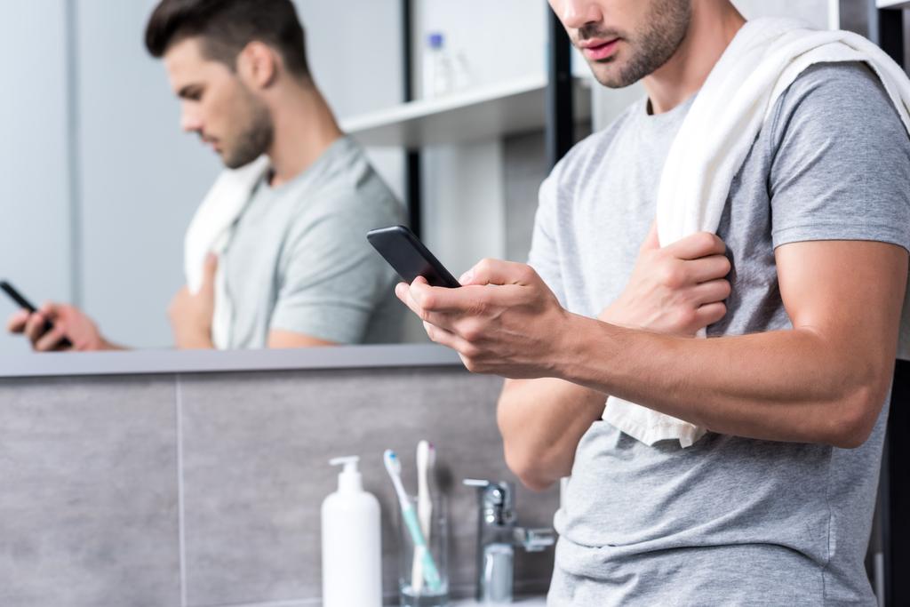 man met smartphone in badkamer - Foto, afbeelding