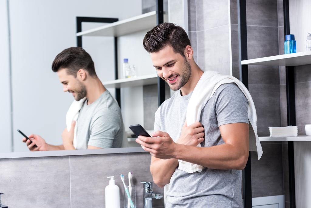 man met smartphone in badkamer - Foto, afbeelding