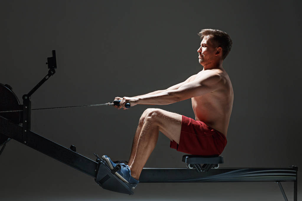 Hombre usando una máquina de prensa en un club de fitness
. - Foto, Imagen