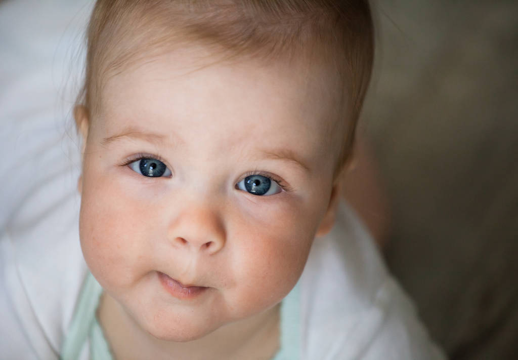 Bebek duygular. Beyaz t shirt mavi gözlü kız bebek cam içinde bakmak ve öpmeye çalışın. Yeni doğan. Yakın çekim. - Fotoğraf, Görsel