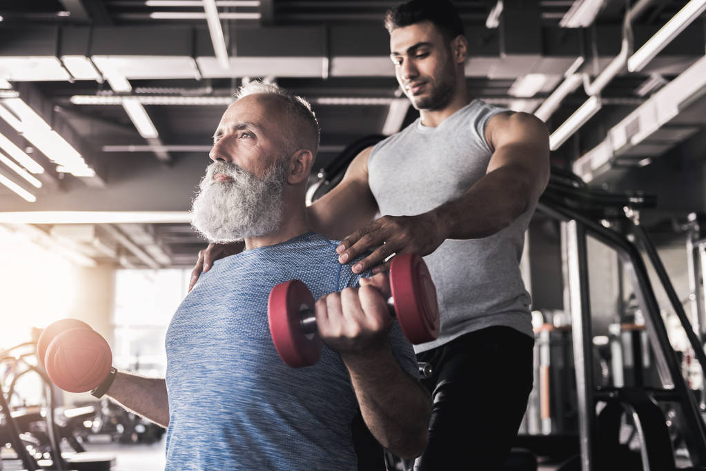 Concentré mâle senior est l'entraînement de ses biceps dans la salle de gym
 - Photo, image