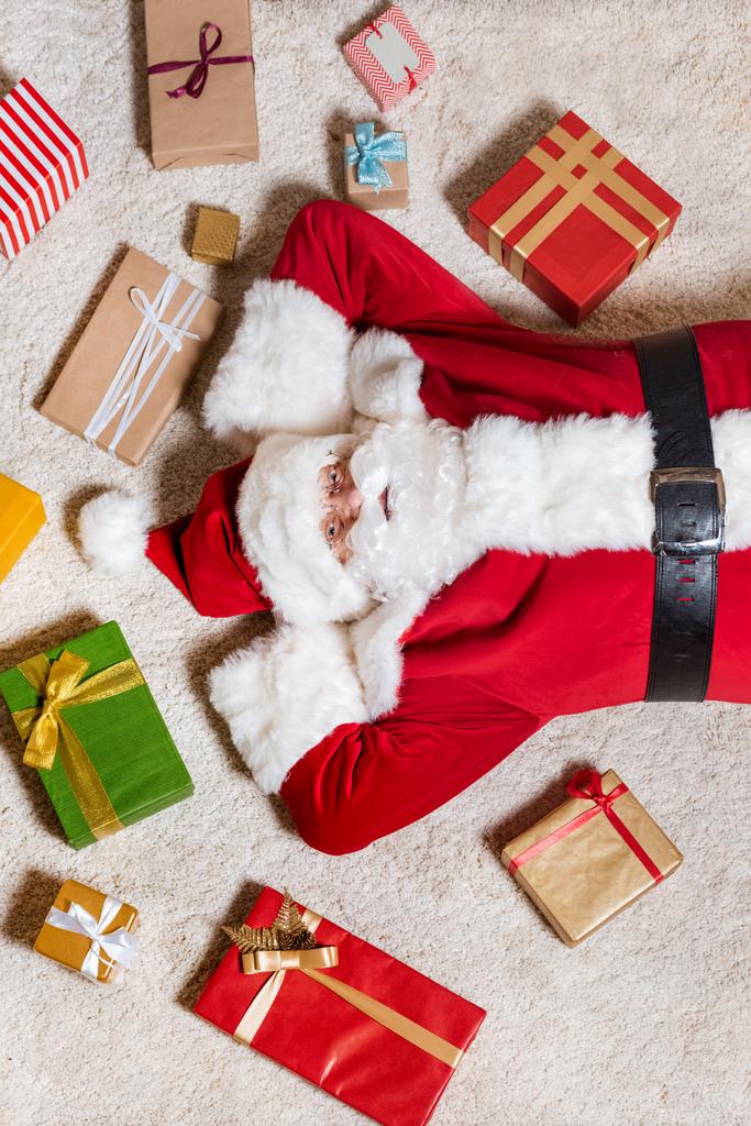Weihnachtsmann liegt mit Geschenken auf dem Boden - Foto, Bild