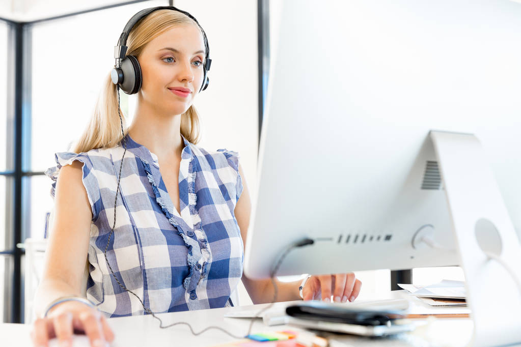 Fiatal nő hallgatta a zenét, miközben dolgozik a számítógépen - Fotó, kép