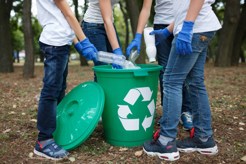 Close-up de crianças mãos em luvas de látex azul segurando lixo plástico em um fundo do parque turvo. Conceito de protecção ecológica
. - Foto, Imagem