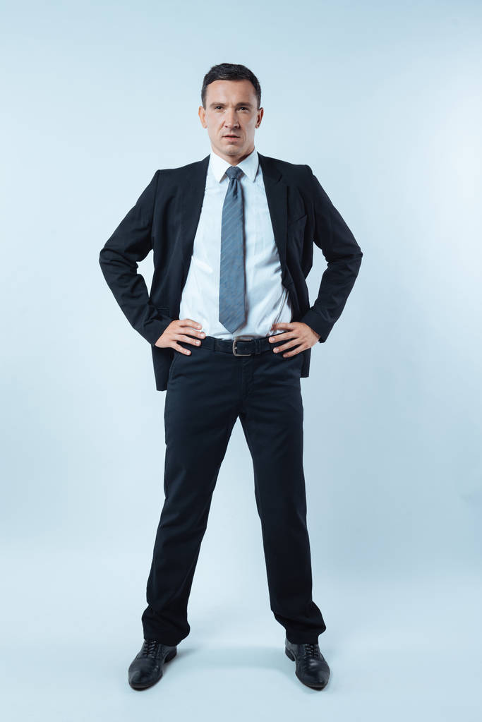 Έξυπνη καλός επιχειρηματίας ψάχνει στέκεται ενάντια σε μπλε φόντο - Φωτογραφία, εικόνα