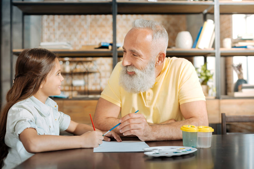 Abuelo sonriente y nieta pintando un cuadro juntos
 - Foto, Imagen