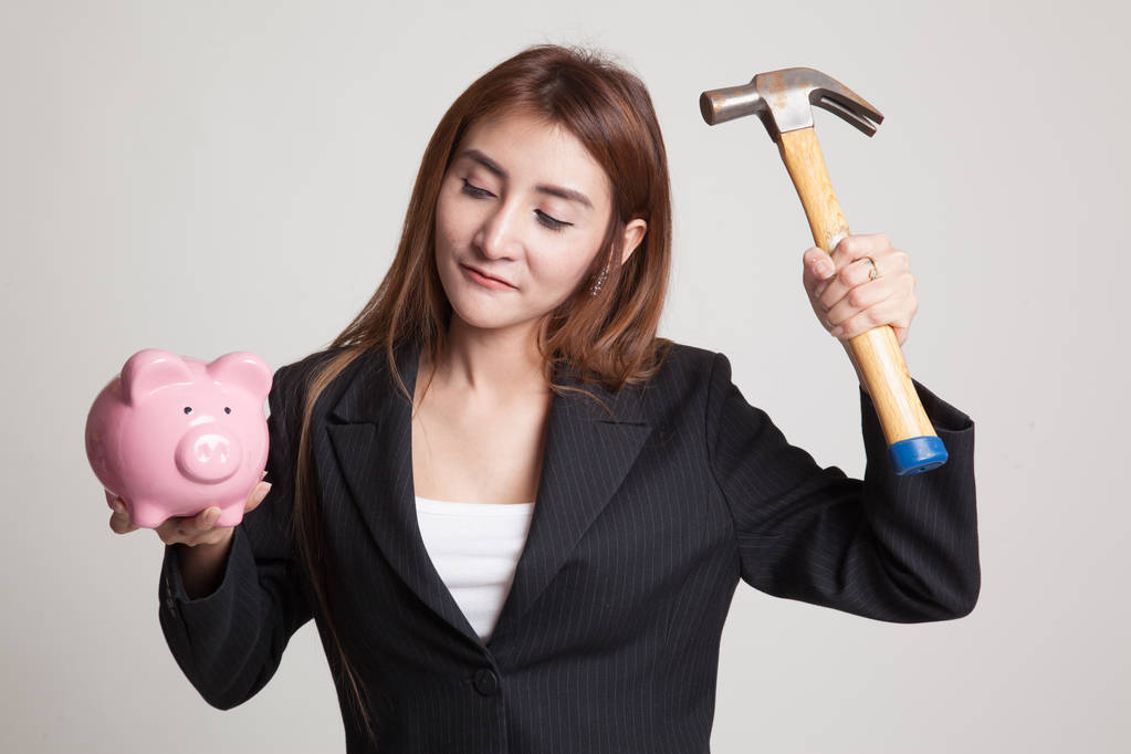 Mujer asiática con banco de monedas de cerdo y martillo
. - Foto, imagen