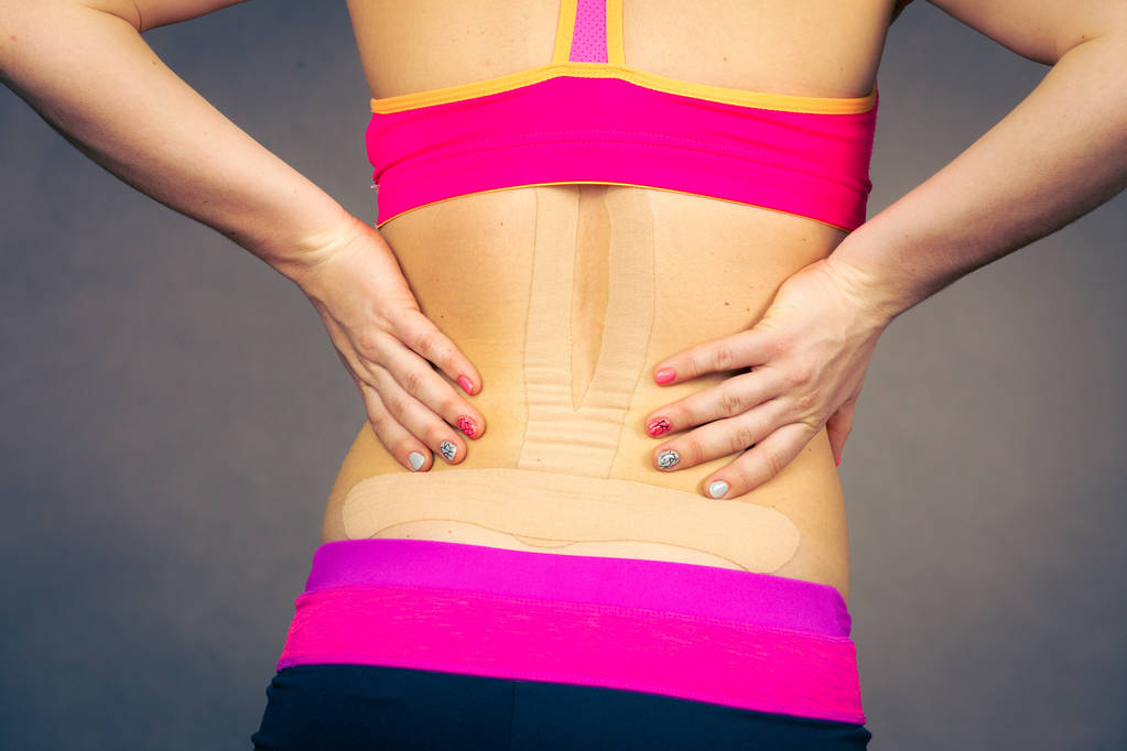 Женщина с медицинским кинезио на спине
 - Фото, изображение
