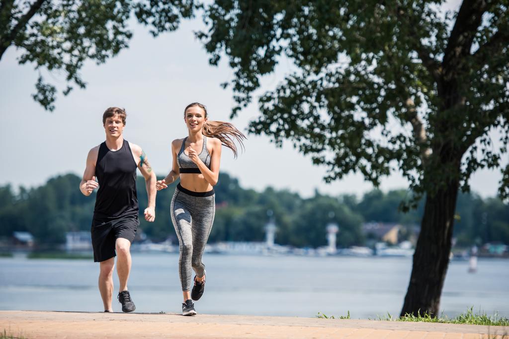 陽気なカップルが公園でジョギング - 写真・画像