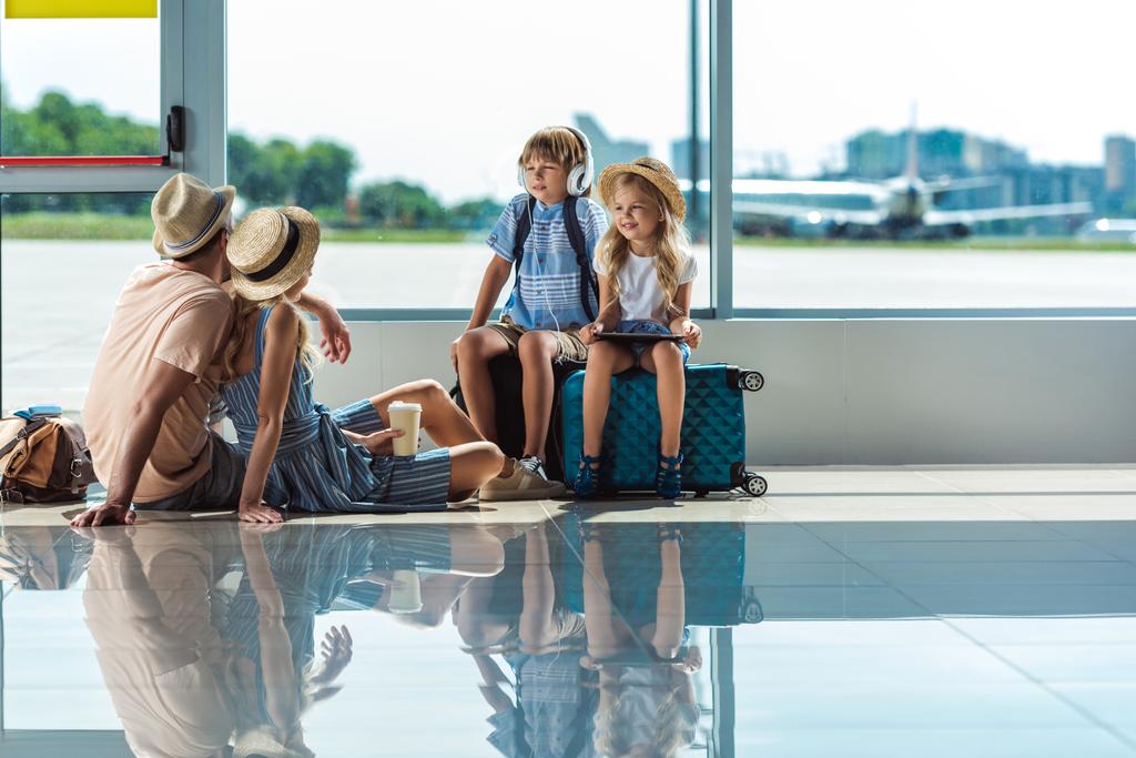 vanhemmat ja lapset odottavat lennolle lentokentällä
 - Valokuva, kuva