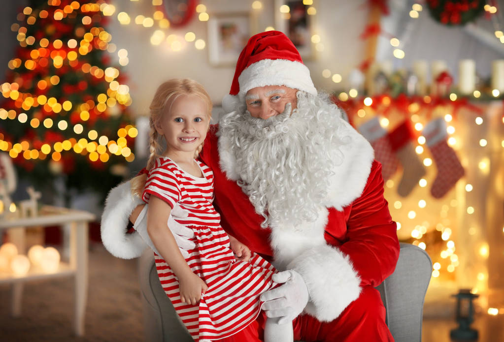 Mała dziewczynka siedzi na kolanach Świętego Mikołaja w pokoju z piękne Dekoracje świąteczne - Zdjęcie, obraz