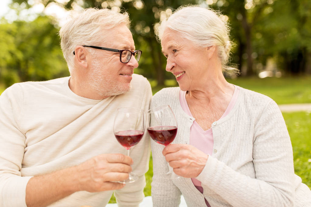 счастливая пожилая пара пьет вино в летнем парке
 - Фото, изображение