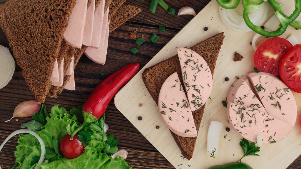 ライ麦パンは、素朴な木製の背景にボイル ソーセージのサンドイッチ - 写真・画像