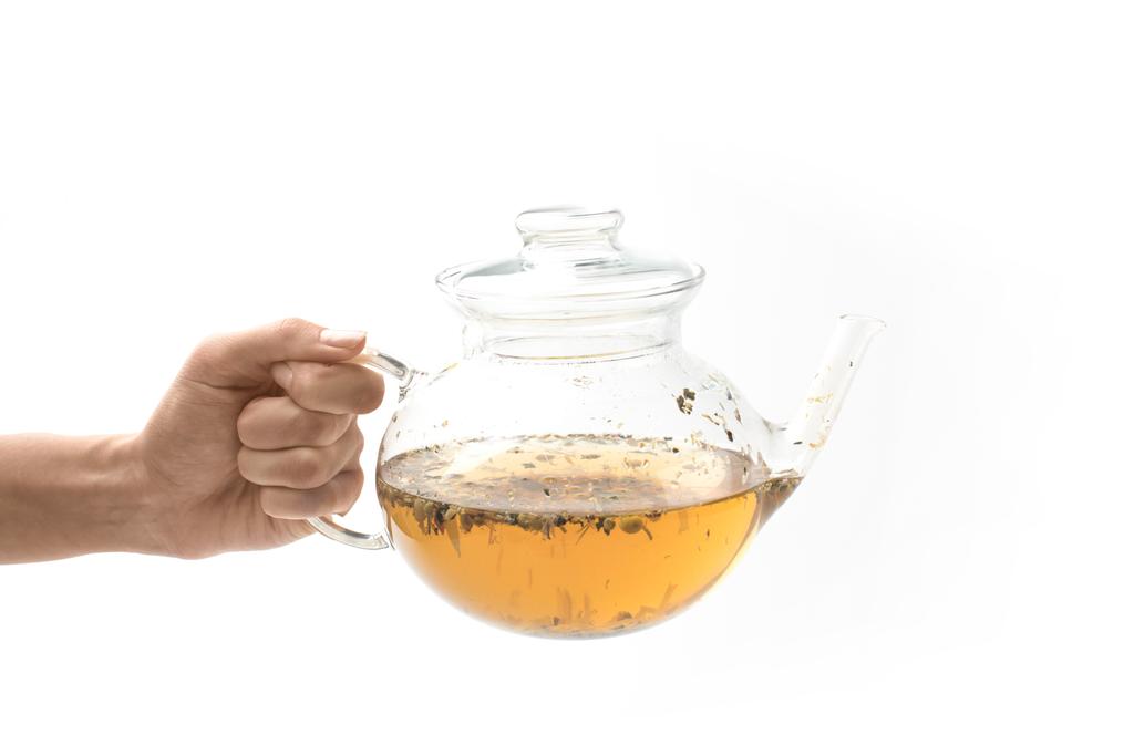 glazen theepot met kruiden thee in de hand - Foto, afbeelding