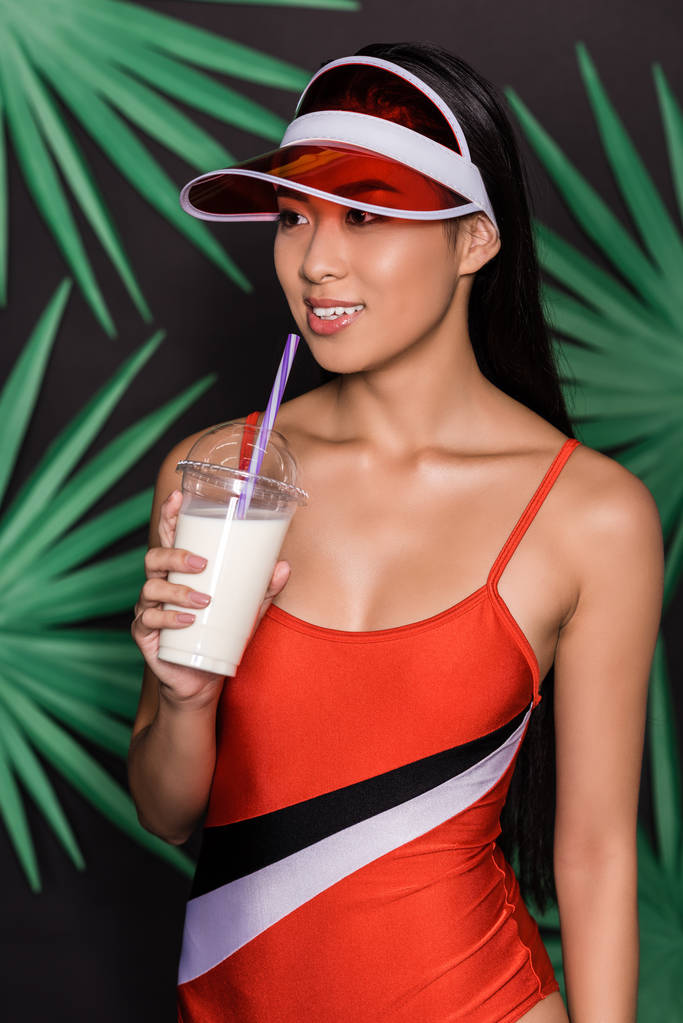 woman in swimsuit and visor drinking milkshake - Photo, Image