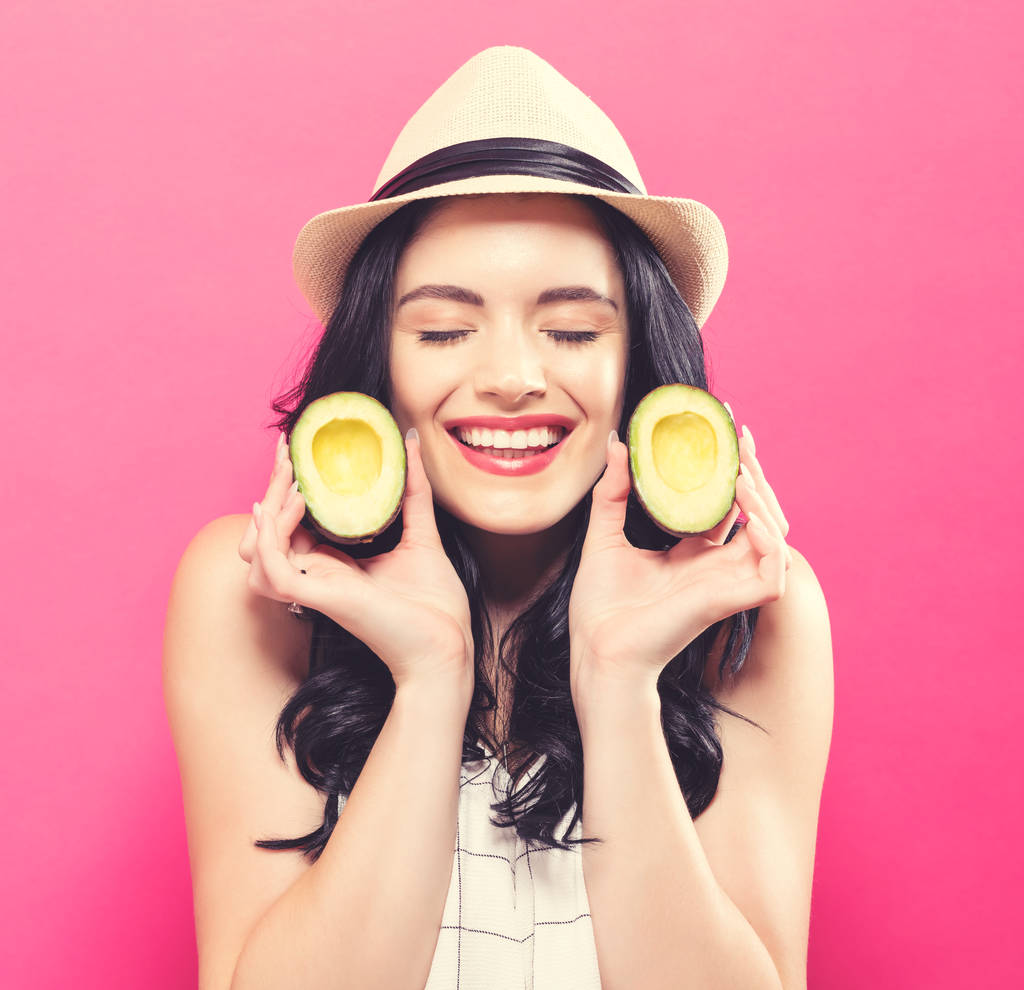 Счастливая молодая женщина с половинками авокадо
  - Фото, изображение