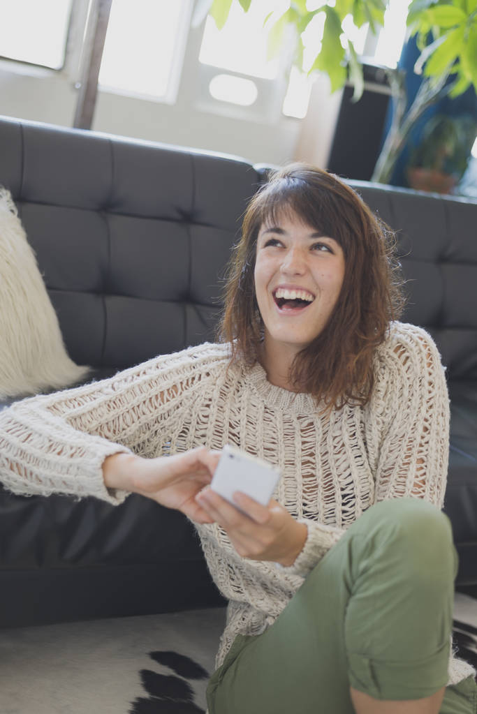Mujer alegre hablando por teléfono móvil, sentada en la sala de estar
 - Foto, imagen