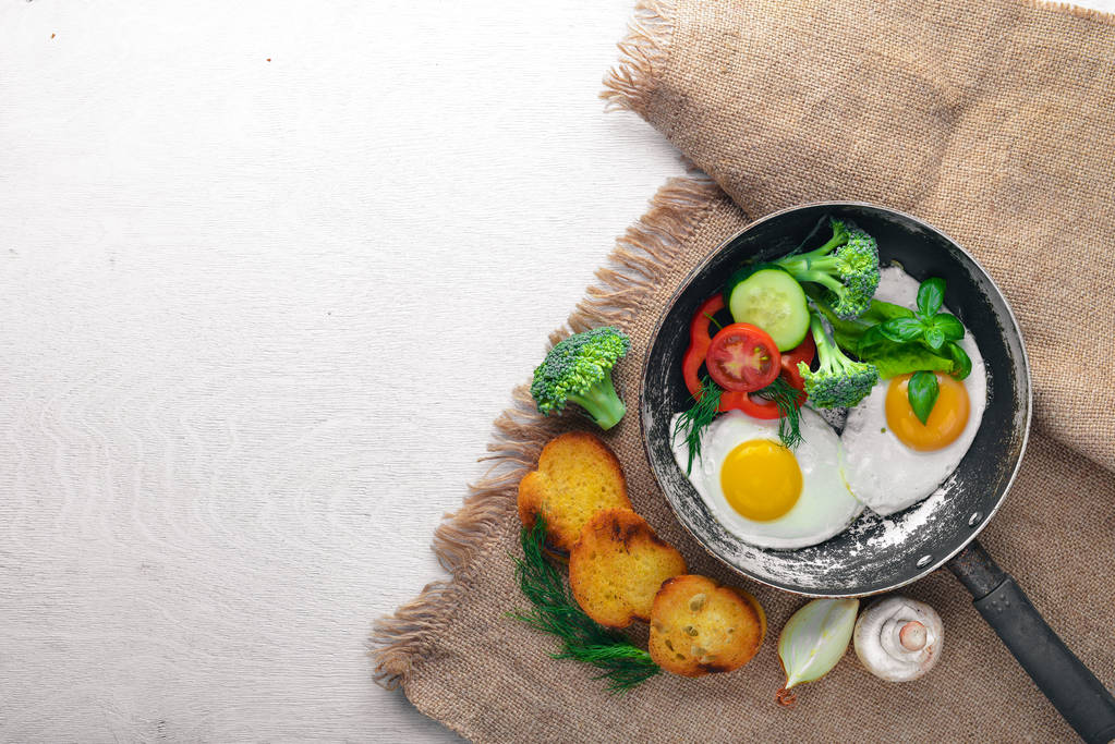 Жареное яйцо с травами, тост хлеб и овощи в сковороде. Вид сверху. Свободное пространство
. - Фото, изображение