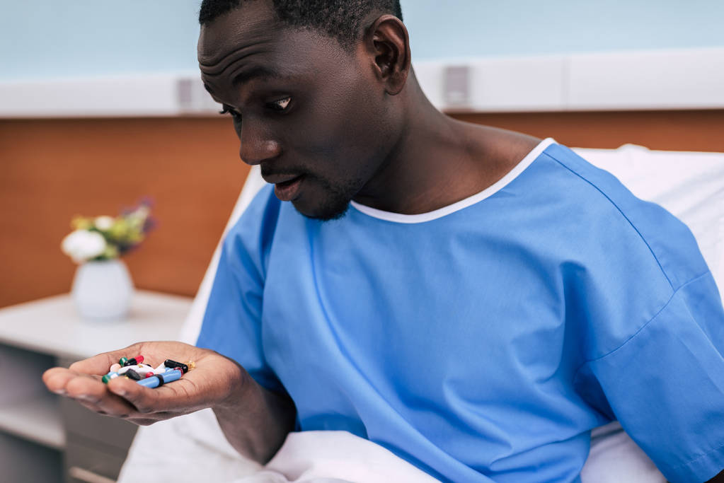 афроамериканський чоловік дивиться на таблетки
 - Фото, зображення
