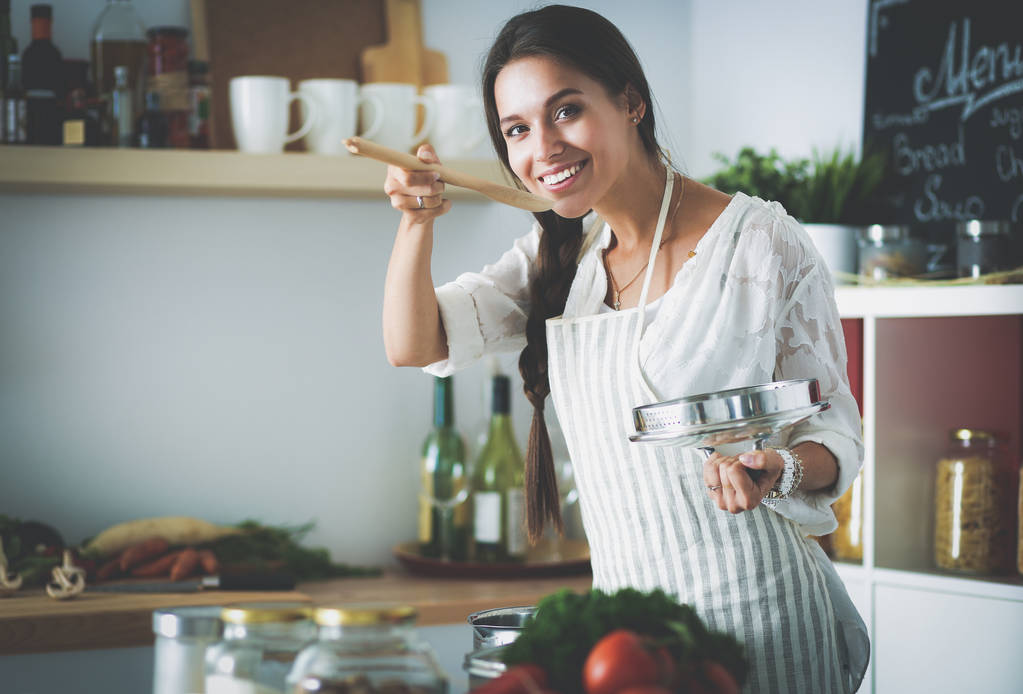 Koken vrouw in keuken met houten lepel - Foto, afbeelding