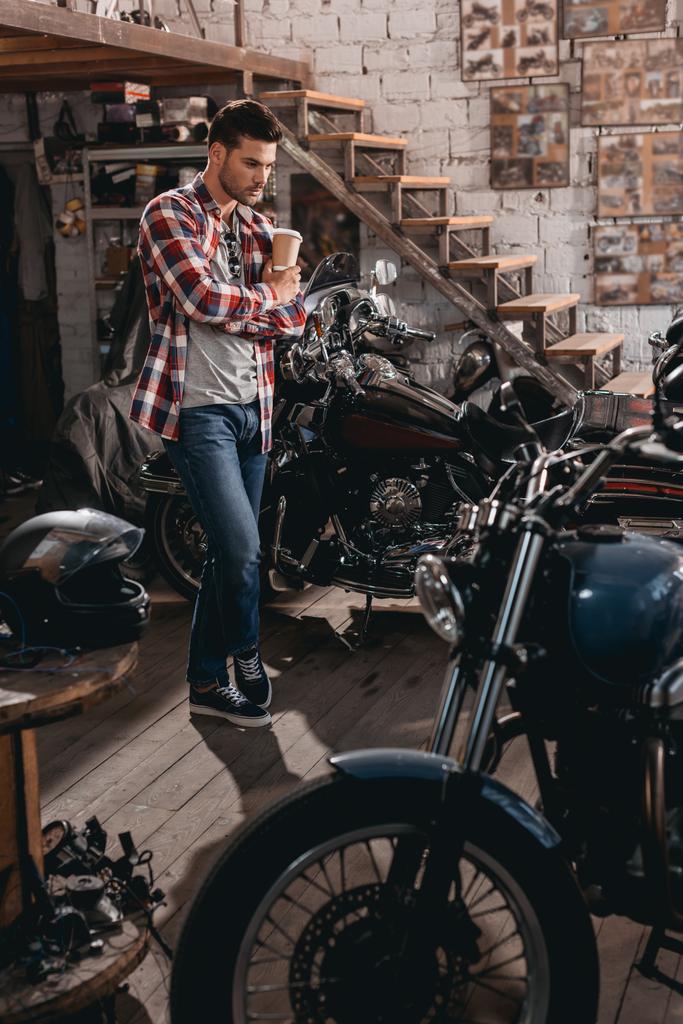 hombre en taller de reparación con motocicletas clásicas
  - Foto, Imagen