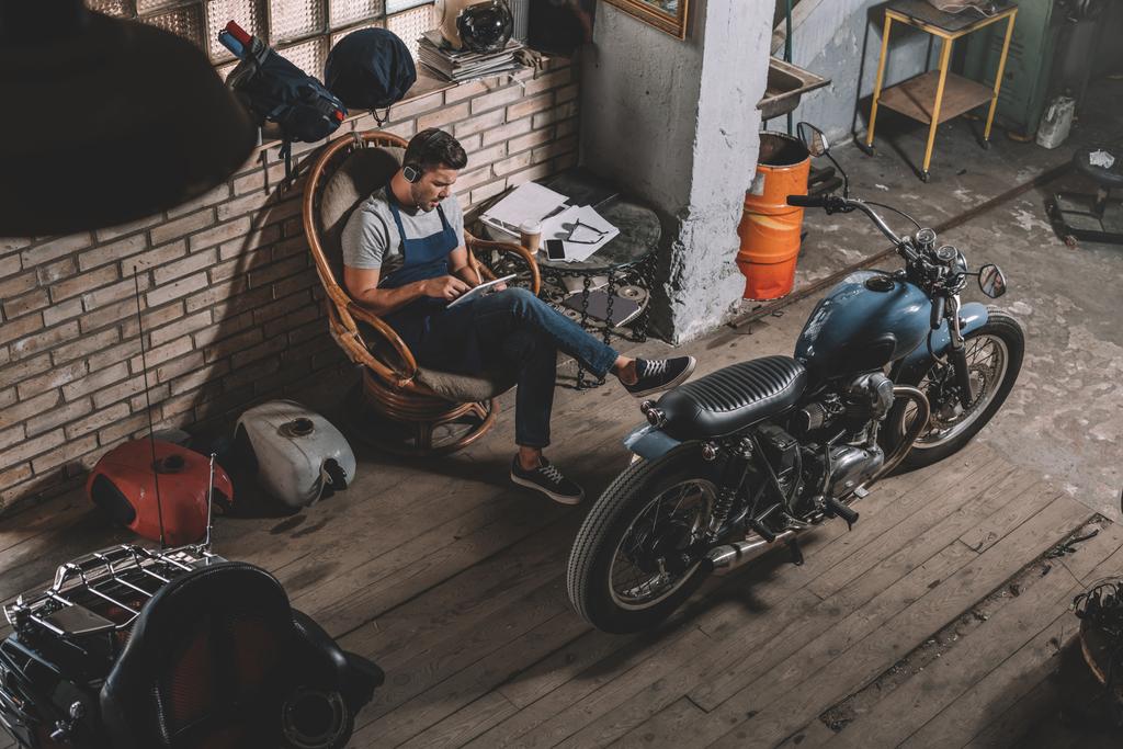 Mechaniker in Werkstatt mit Motorrad - Foto, Bild