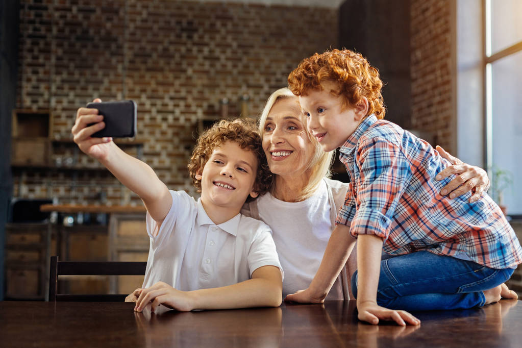 Petits-enfants prenant selfies avec grand-mère joyeuse
 - Photo, image