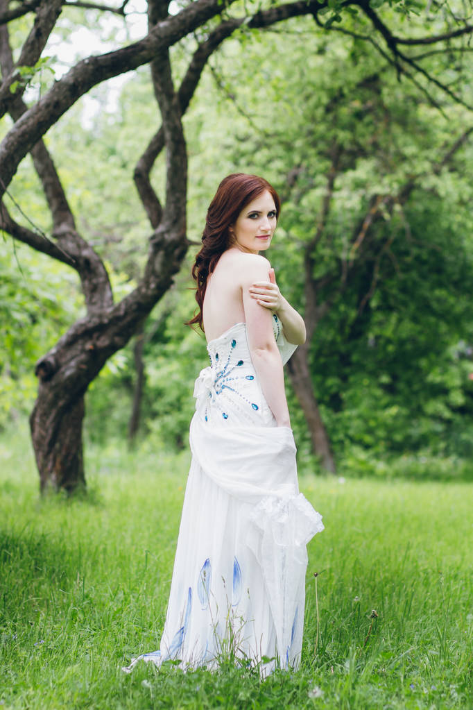 夏の庭に長い白いドレスを着た女性  - 写真・画像