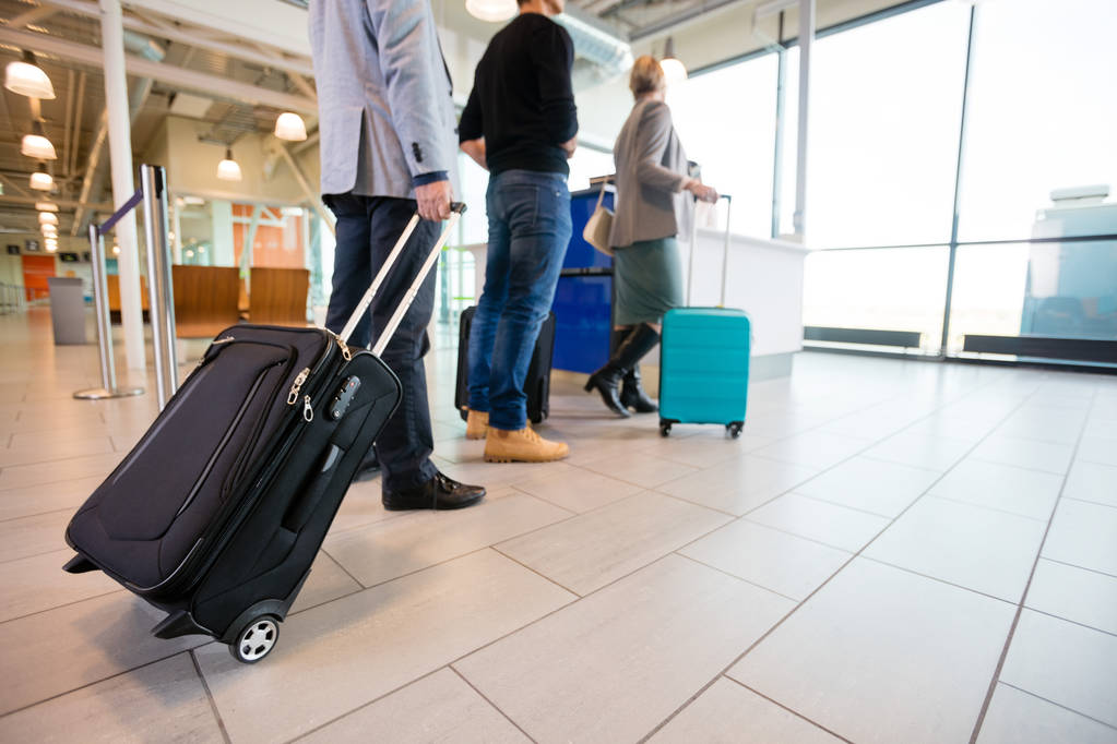 Пассажиры, стоящие на этаже с багажом на стойке регистрации аэропорта А
 - Фото, изображение