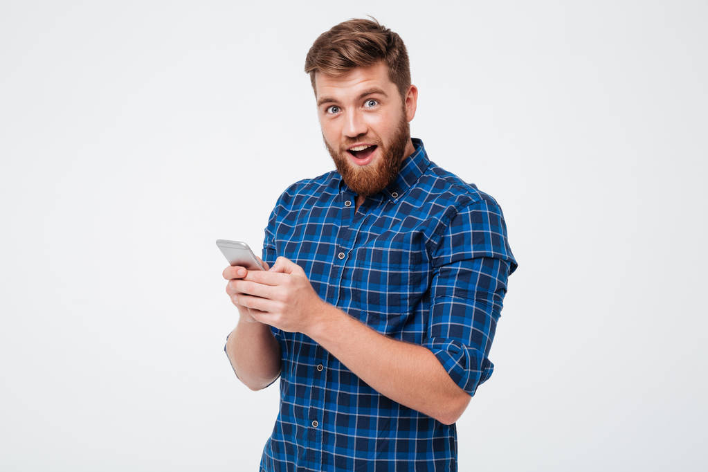 Έκπληκτος ο άνθρωπος σε καρώ πουκάμισο χρησιμοποιώντας smartphone - Φωτογραφία, εικόνα