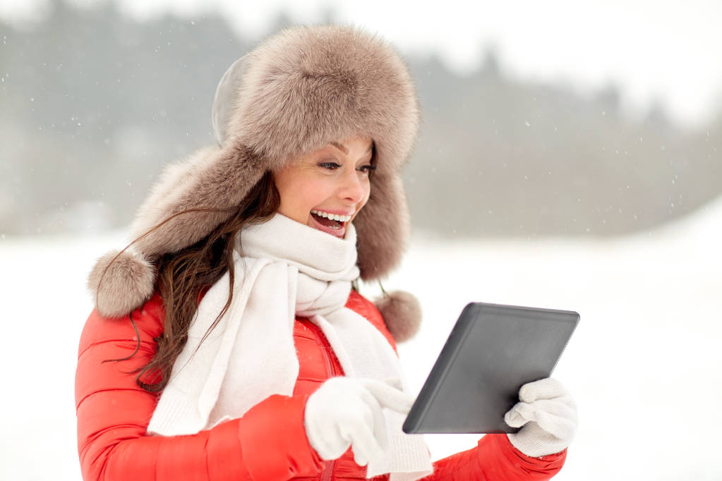 woman in winter fur hat with tablet pc outdoors - Photo, Image
