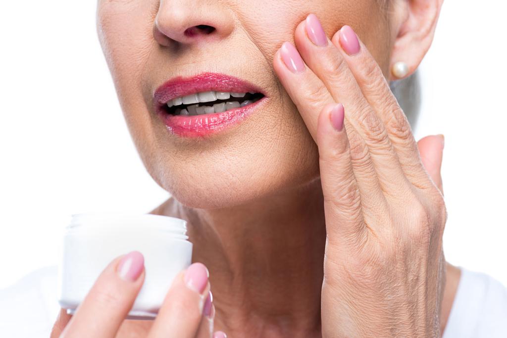 Mujer mayor aplicando crema facial
  - Foto, Imagen
