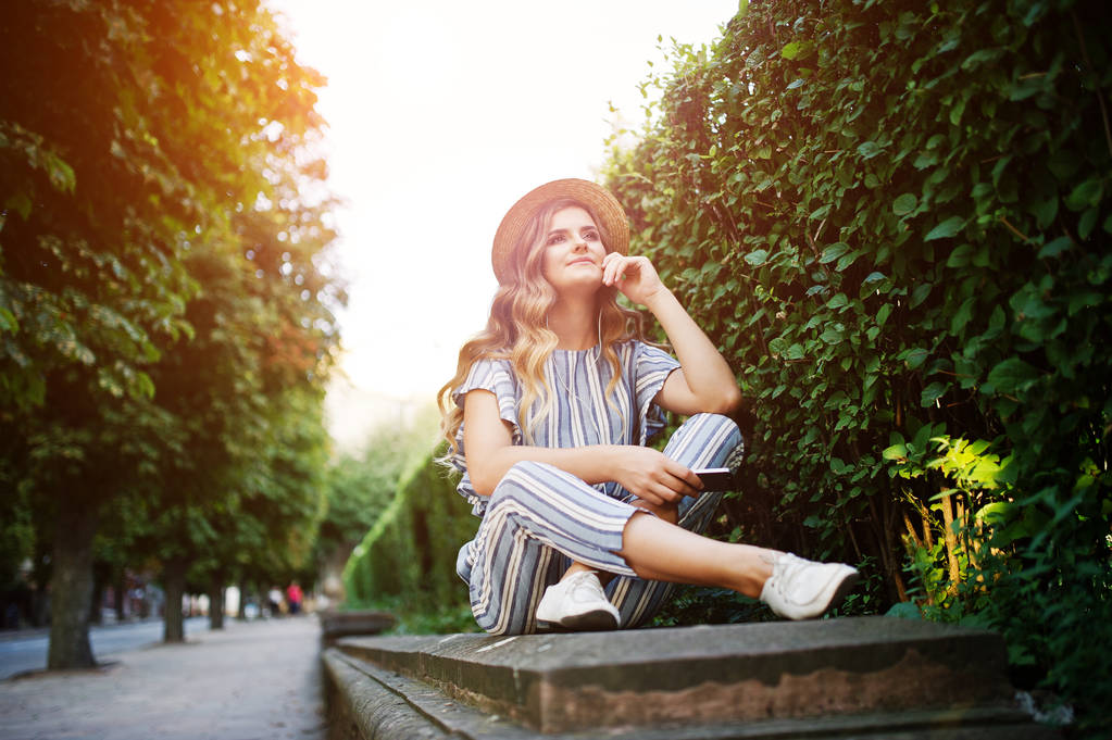 Portrait of a stunning young woman in striped overall sitting in - Photo, Image