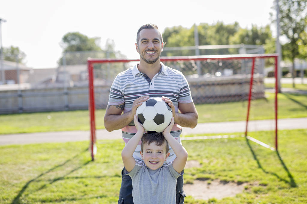 ο άνθρωπος με το παιδί που παίζει ποδόσφαιρο στο πεδίο - Φωτογραφία, εικόνα