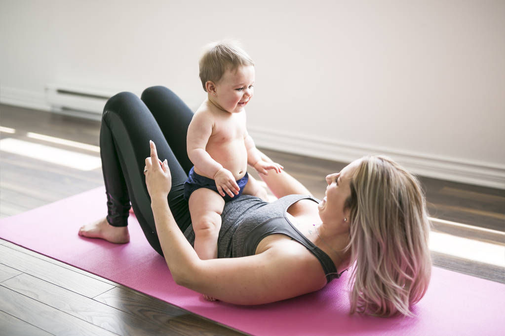 nuori äiti tekee fyysisiä joogaharjoituksia yhdessä vauvansa kanssa - Valokuva, kuva
