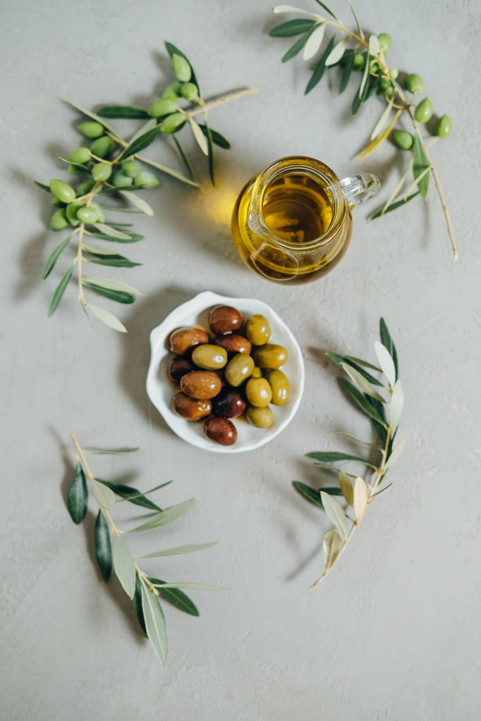 Pohled shora olivy, olej a zelené větve na šedém pozadí - Fotografie, Obrázek