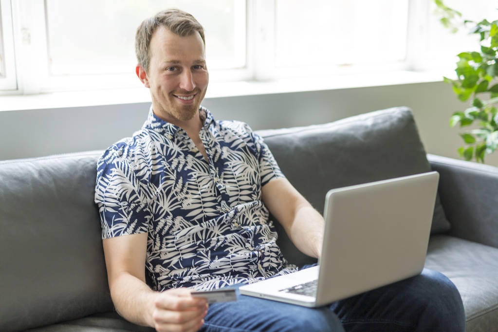 Щасливий чоловік купує онлайн у своїй вітальні
 - Фото, зображення