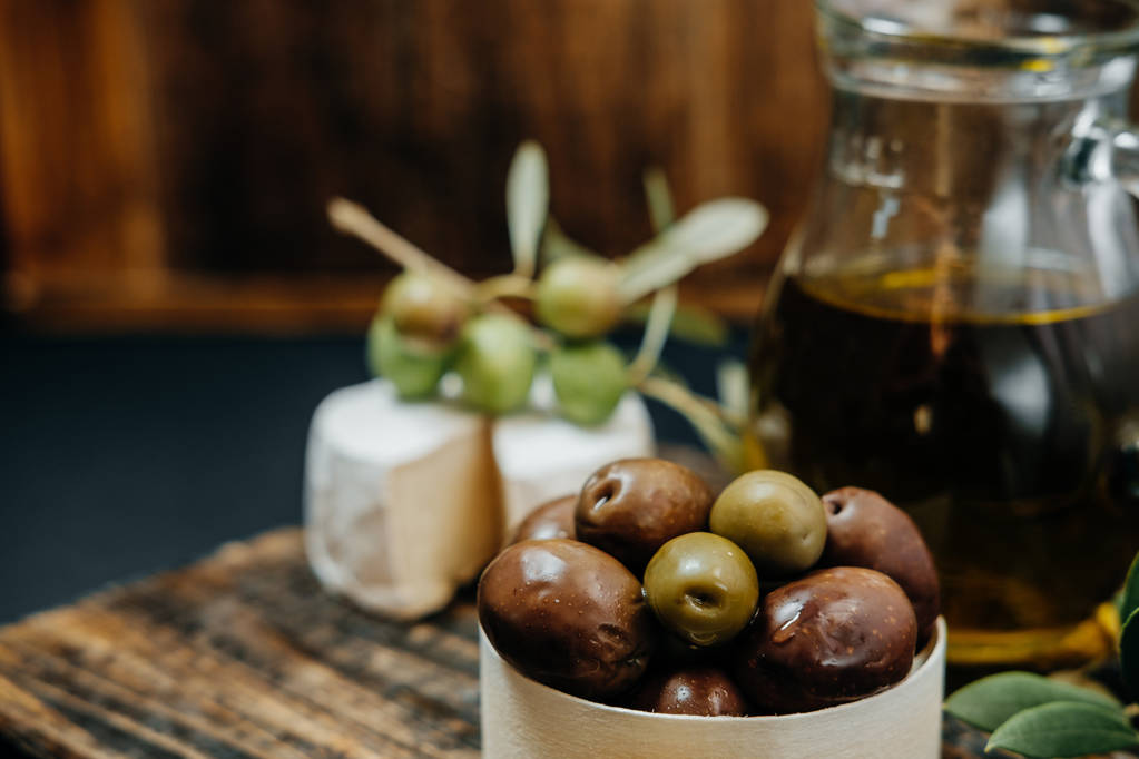 Svačina: tmavý a zelené olivy, olej, kozí sýr na dřevo - Fotografie, Obrázek