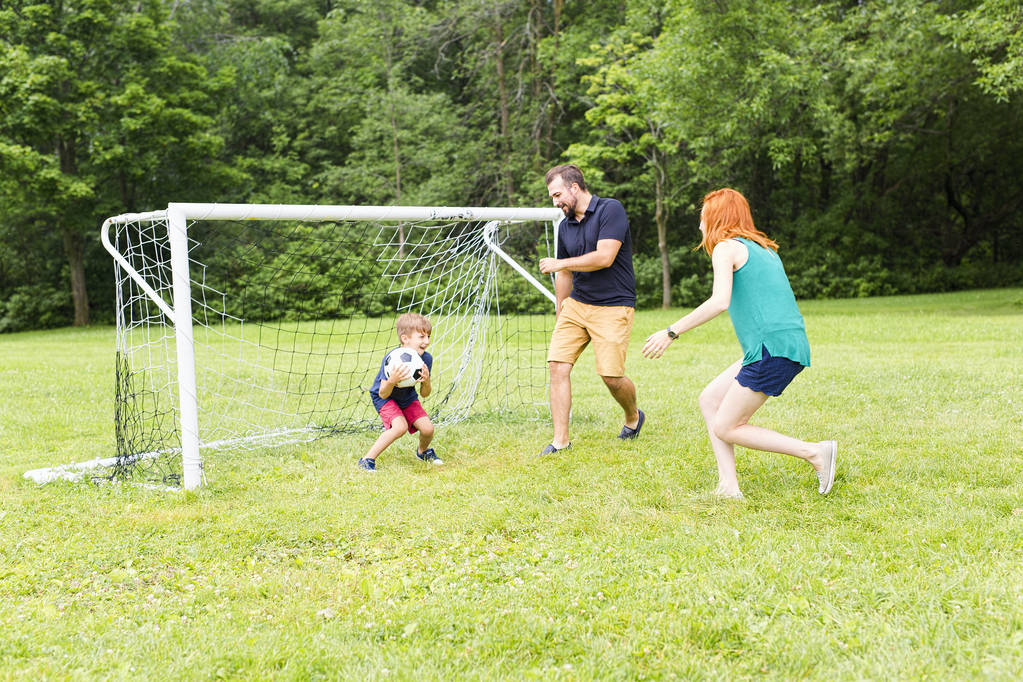 Famille joyeuse jouant au football dans un parc
 - Photo, image