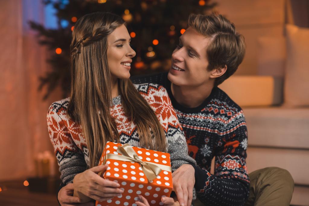 мужчина обнимает девушку с подарком на Рождество
 - Фото, изображение