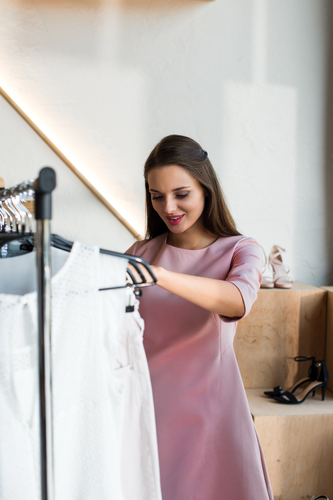 Mujer joven eligiendo ropa en boutique
 - Foto, imagen