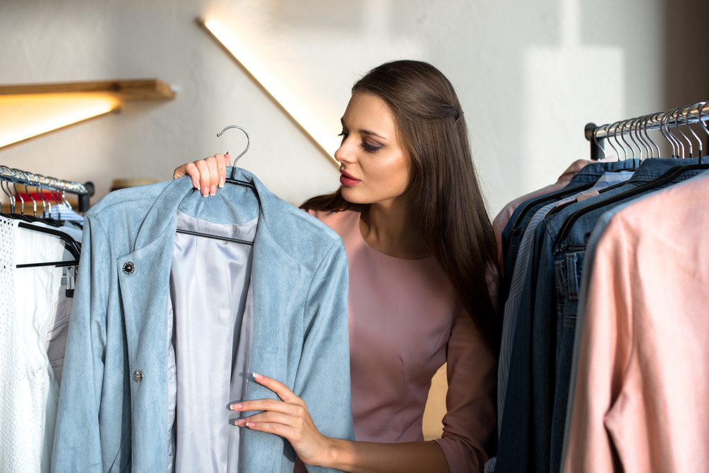 Jovem mulher escolhendo roupas em boutique
 - Foto, Imagem